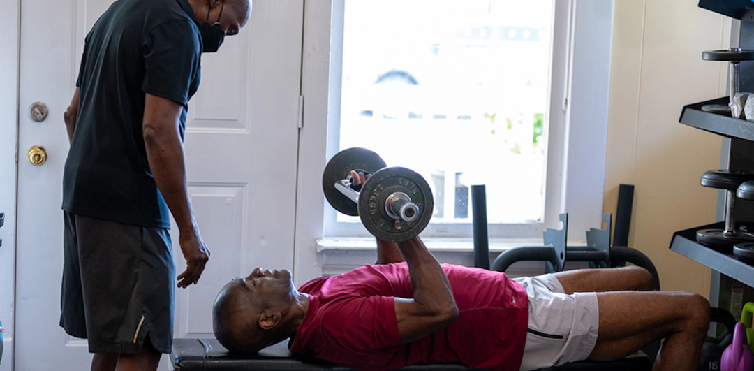 A trainer working with a man doing bench presses.